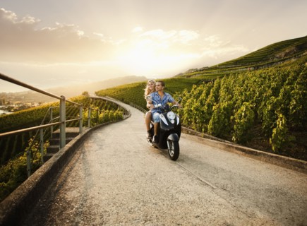Couple riding scooter in vineyard