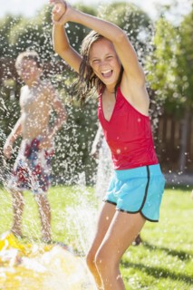 Caucasian girl playing in sprinkler