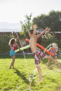 Caucasian children playing in the sprinkler
