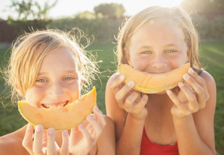 Caucasian girls eating cantaloupe