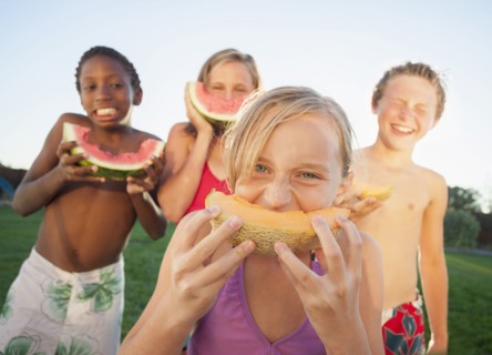 Children eating cantaloupe and watermelon