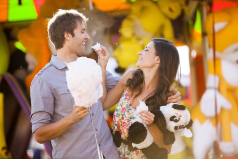 Caucasian couple sharing cotton candy at carnival