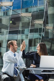 Caucasian business people high fiving at desk