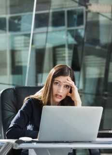 Stressed Caucasian businesswoman at laptop