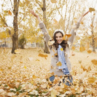 Caucasian woman playing in autumn leaves