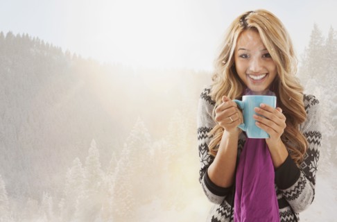Mixed race woman drinking coffee in snow