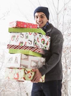 Hispanic man holding Christmas gifts in snow