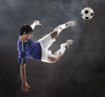 Hispanic soccer player kicking ball in mid air