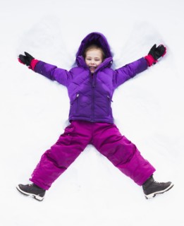 Caucasian girl making snow angel outdoors
