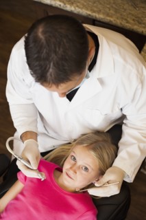 Caucasian dentist examining girl's teeth in office