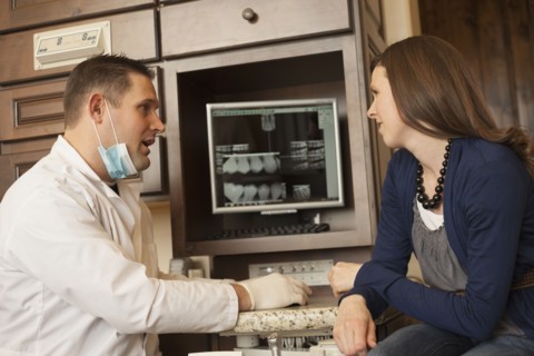 Caucasian dentist and woman talking in office