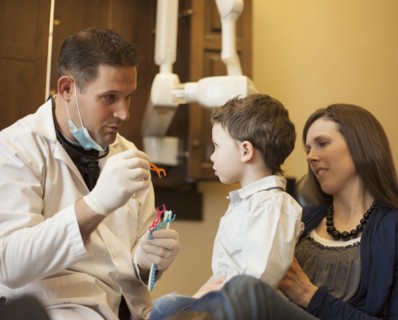 Dentist and nurse examining boy's teeth in office