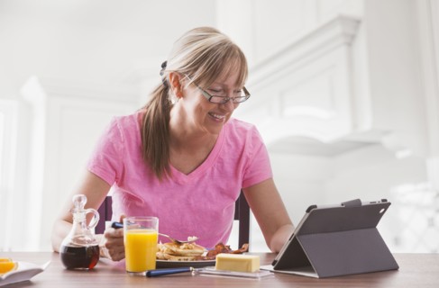 Caucasian woman using tablet computer at breakfast