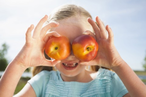 Caucasian girl holding fruit over eyes