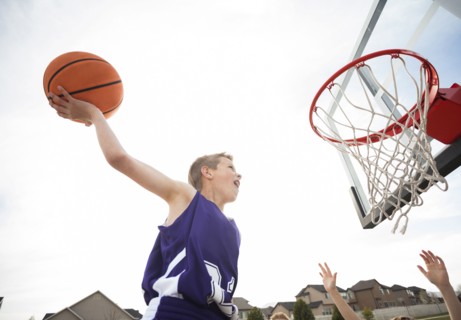 Caucasian boy dunking basketball in hoop