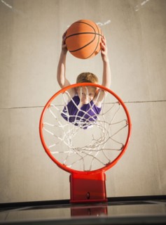 Caucasian boy dunking basketball in hoop