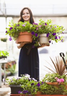 Caucasian woman holding potted flowers in plant nursery