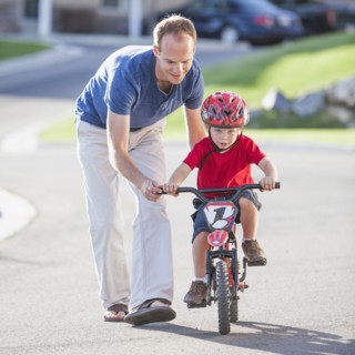 Caucasian father teaching son to ride bicycle