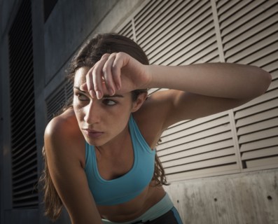 Caucasian runner wiping sweat off forehead