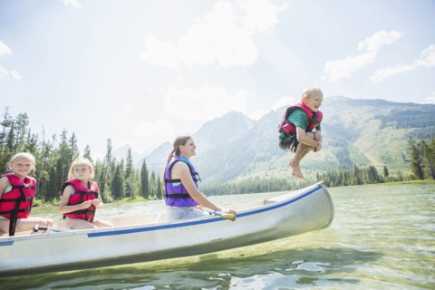 Caucasian boy jumping from canoe into lake