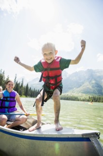 Caucasian boy standing on canoe on lake