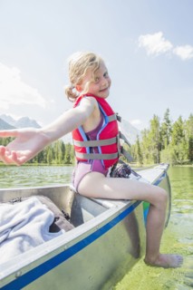 Caucasian girl sitting on top of canoe on lake