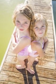 Caucasian girls standing back to back on dock