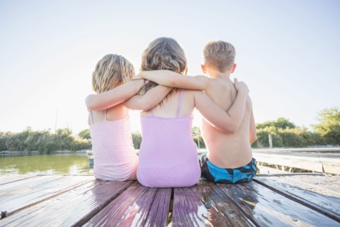 Caucasian children sitting on dock