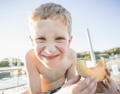 Caucasian boy eating cantaloupe slice