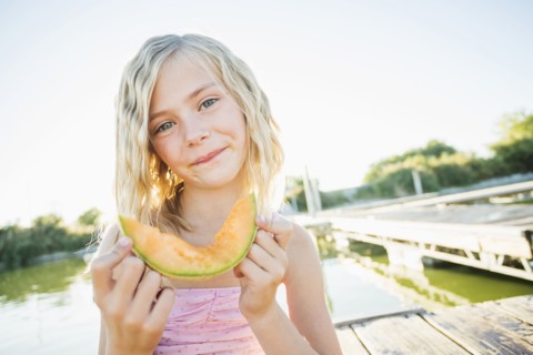 Caucasian girl eating cantaloupe slice