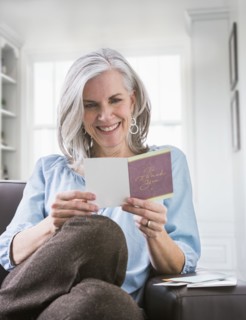 Happy Caucasian woman reading card on sofa