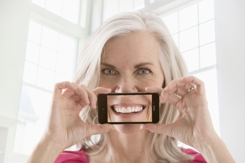 Caucasian woman holding cell phone with image of smile