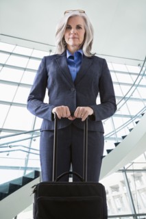 Portrait of confident Caucasian businesswoman with suitcase