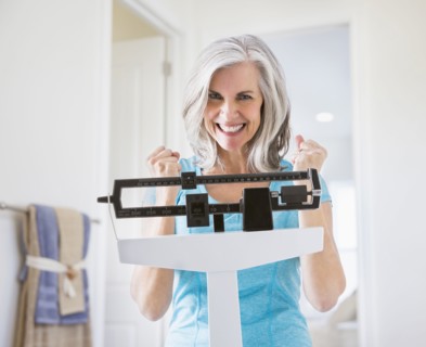 Excited Caucasian woman cheering on weight scale