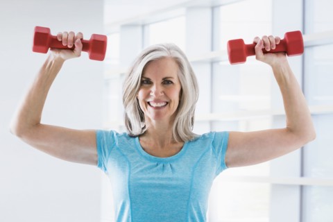 Portrait of confident Caucasian woman lifting dumbbells