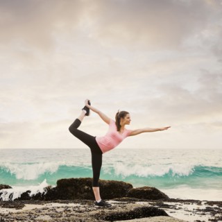 Caucasian woman stretching on beach