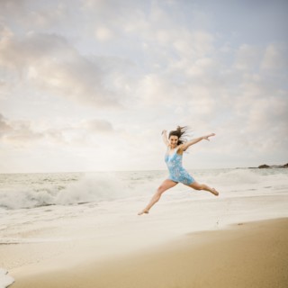 Caucasian woman jumping on beach
