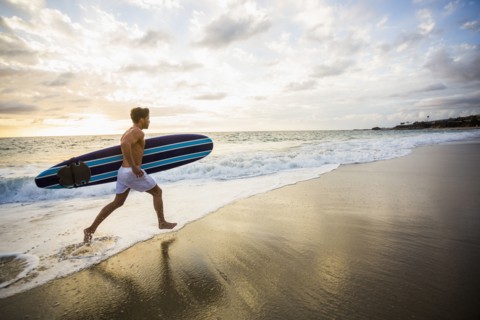 Caucasian surfer carrying board in waves