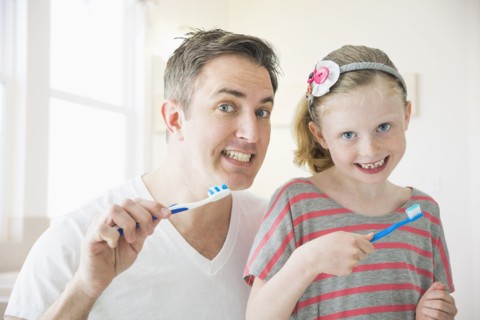 Caucasian father and daughter brushing their teeth