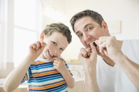 Caucasian father and son flossing their teeth