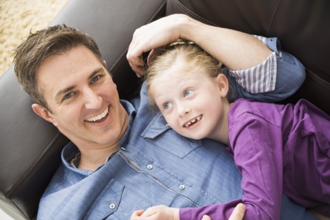 Caucasian father and daughter relaxing on sofa