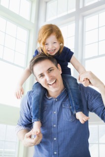 Caucasian father carrying daughter on shoulders