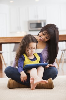 Mother and daughter using tablet computer on living room floor