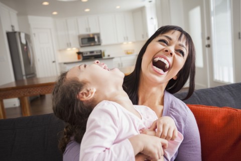 Mother and daughter playing on sofa