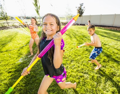 Caucasian children playing in sprinkler in backyard