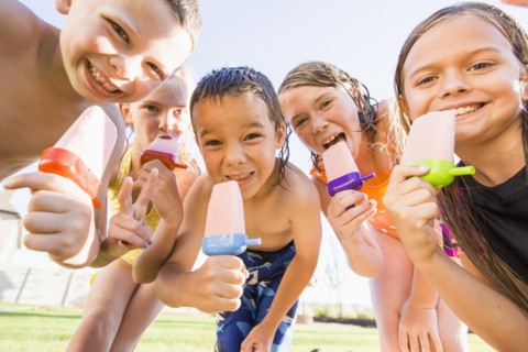 Caucasian children eating popsicles outdoors