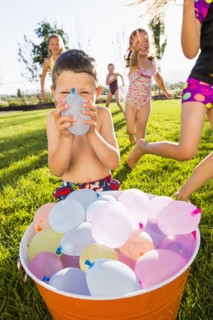 Caucasian children playing with water balloons in backyard