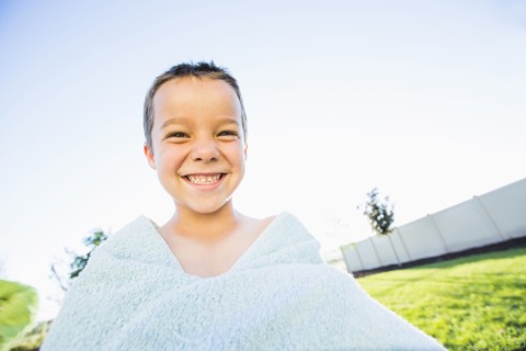 Caucasian boy playing with towel in backyard
