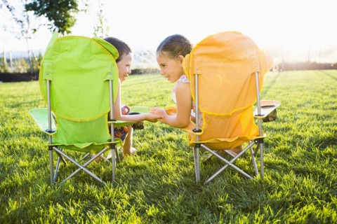 Caucasian children relaxing in lawn chairs in backyard
