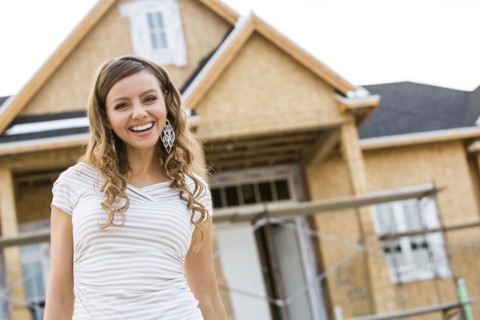 Caucasian woman smiling near house under construction